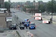 Three unmarked police vehicles block a car from exiting an alley.