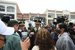 police and protesters surrounded by press