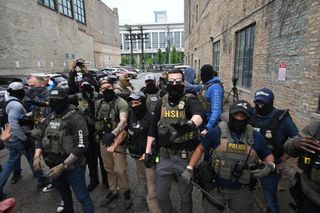 masked ICE agents with olive body armor carriers and black batons